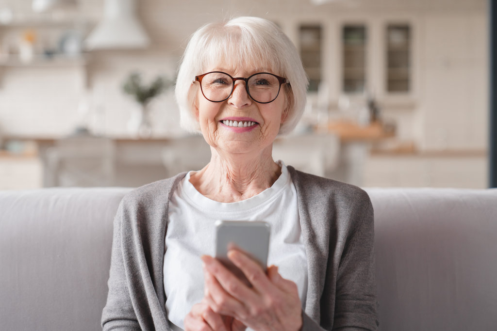 Closeup cropped front view photo of senior old elderly caucasian woman grandmother using smart phone cellphone for e-banking e-commerce, surfing social media online at home