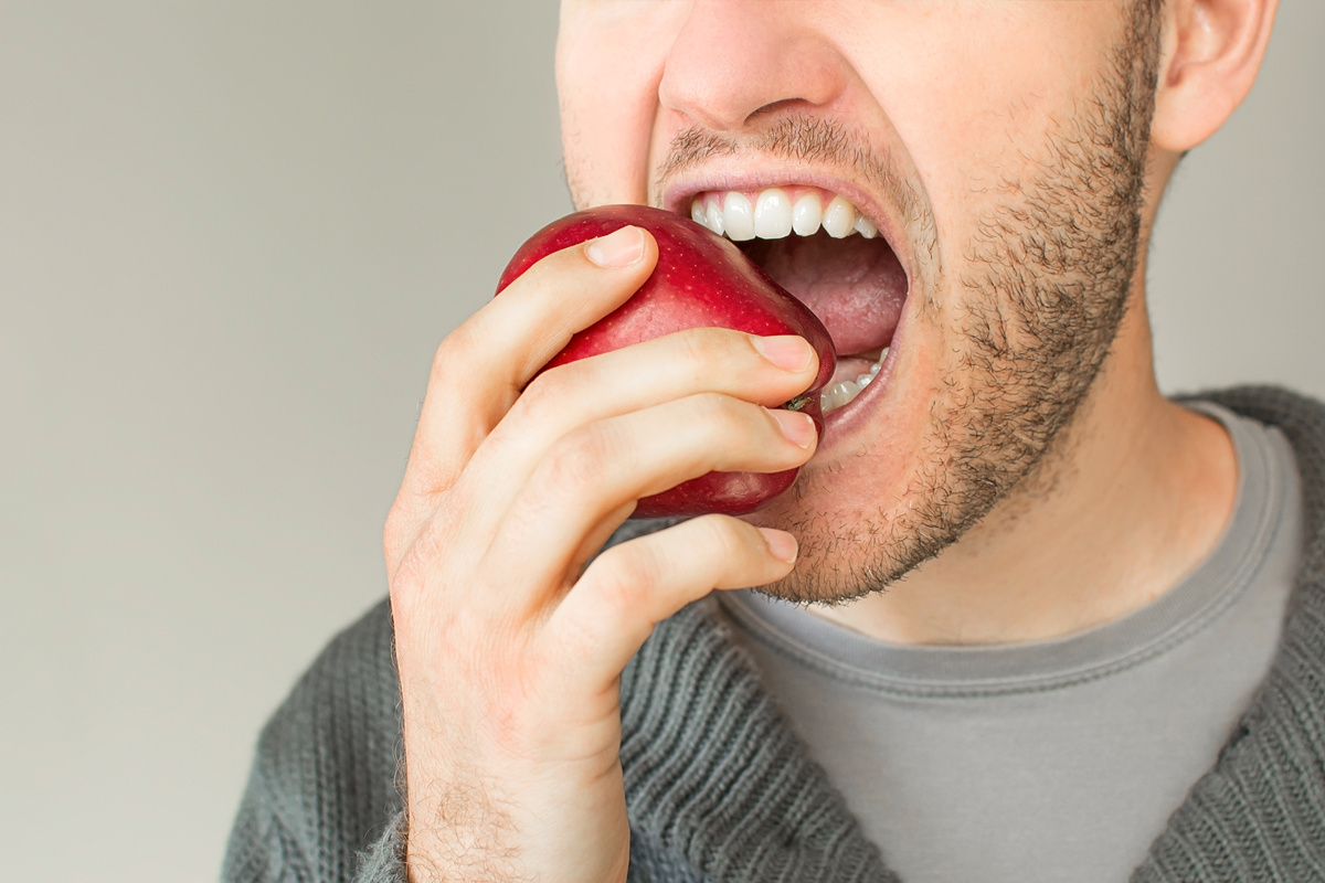 Closeup of man with beard biting an apple